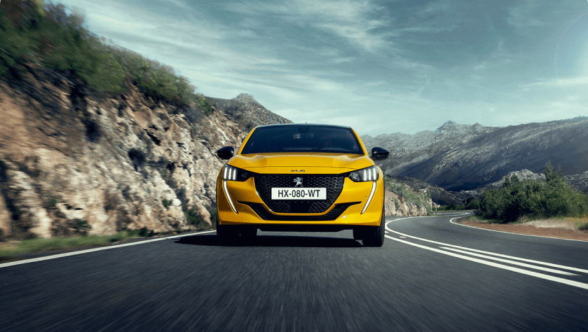 A yellow Peugeot 208 on the road